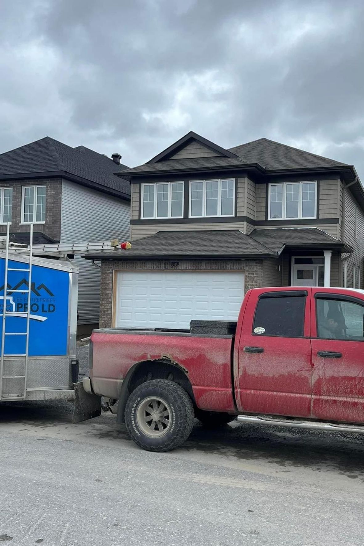Maison en construction avec camion et remorque stationnés devant façade à Low