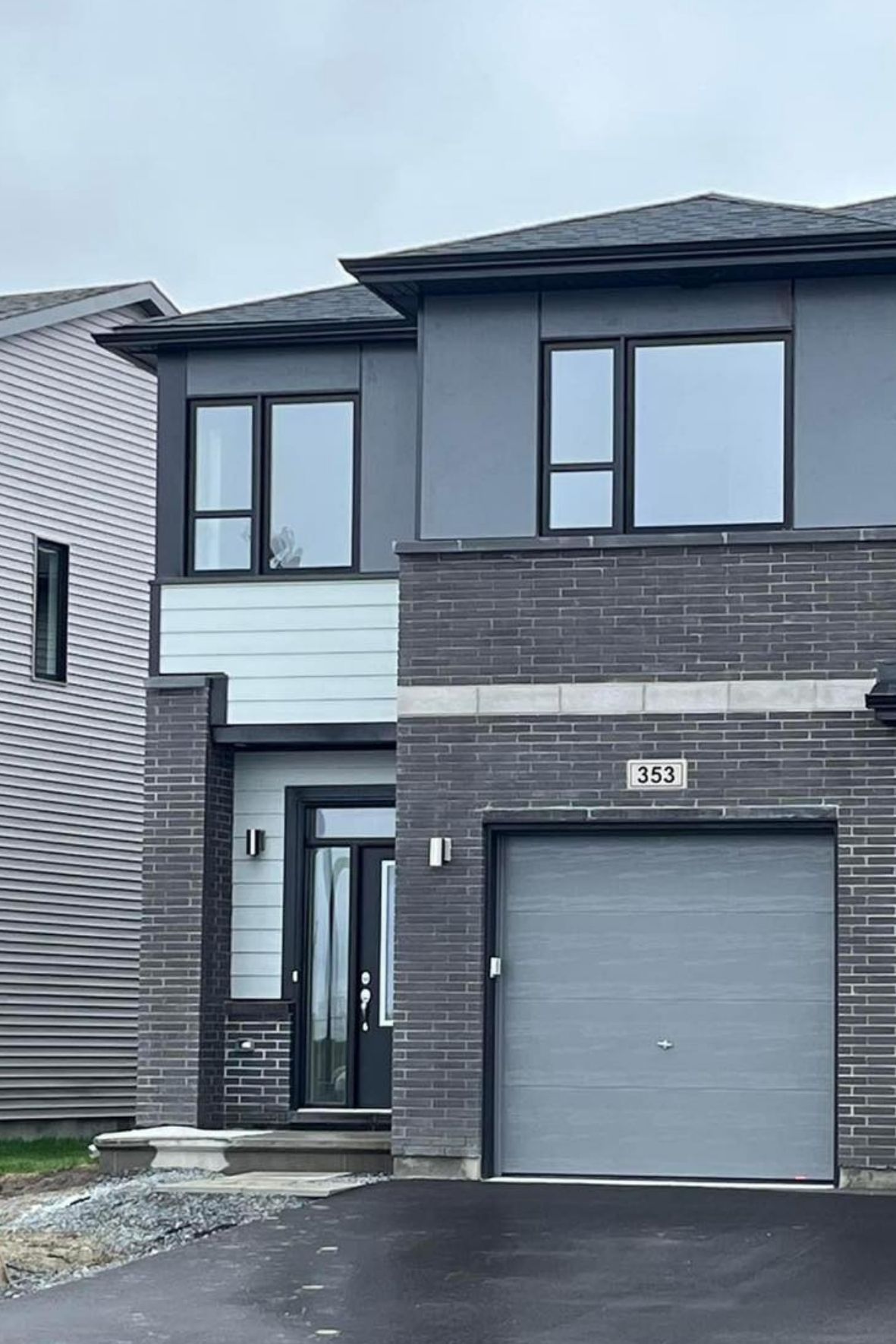 Façade de maison moderne avec revêtement mixte et garage intégré  à Val-des-Monts